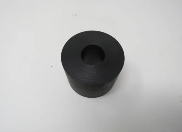 A black rubber bushing sitting on top of a table.