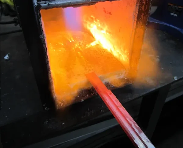 A glass furnace with a red rod in it.