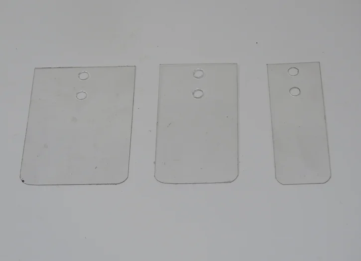 Three pieces of plastic are shown on a white surface.